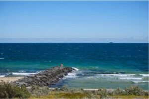 Young man sits on a rock near the ocean contemplating the meaning of life.