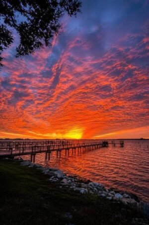 Fiery orange and red sky over a wooden pier at sunset, Dunedin FL