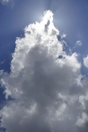 Summer clouds backlit by the sun on a clear blue day.