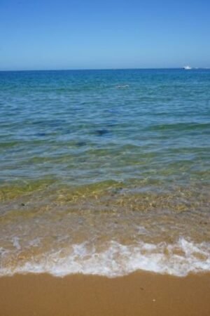 Clear turquoise water and small waves on a sandy beach at Elwood Beach, Australia